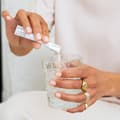 Donna che versa The Solution in un bicchiere d'acqua