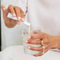 Donna che versa The Solution in un bicchiere d'acqua